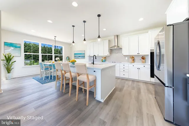 a kitchen with stainless steel appliances a dining table chairs stove refrigerator and wooden floor