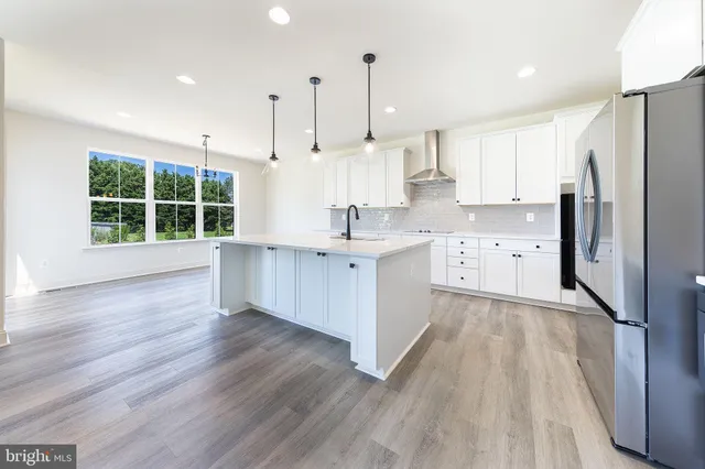 a kitchen with stainless steel appliances granite countertop a refrigerator a sink dishwasher a stove and a wooden floors