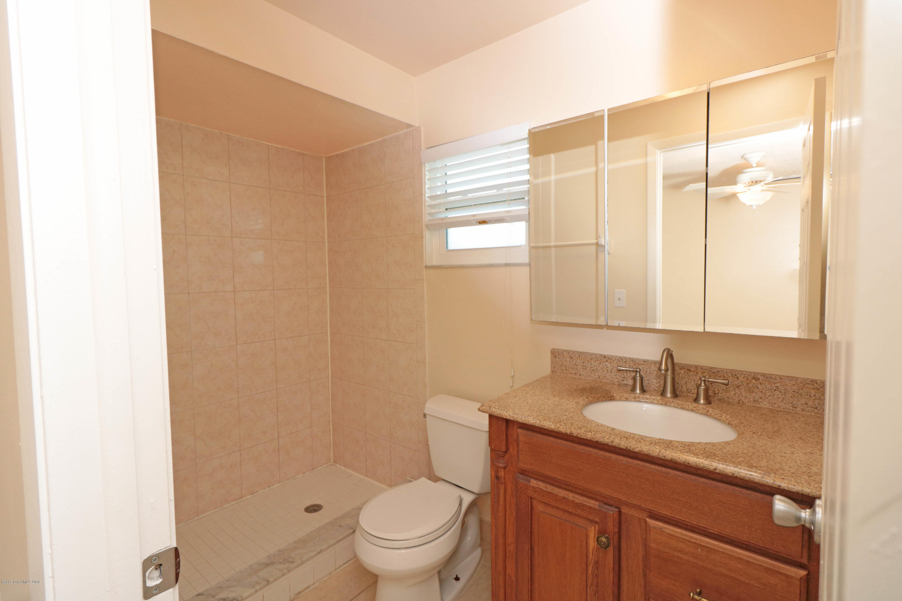 243 Ocean View Lane Melbourne, FL 32903 - Photo 15 of 18 a bathroom with a granite countertop sink toilet a mirror and shower