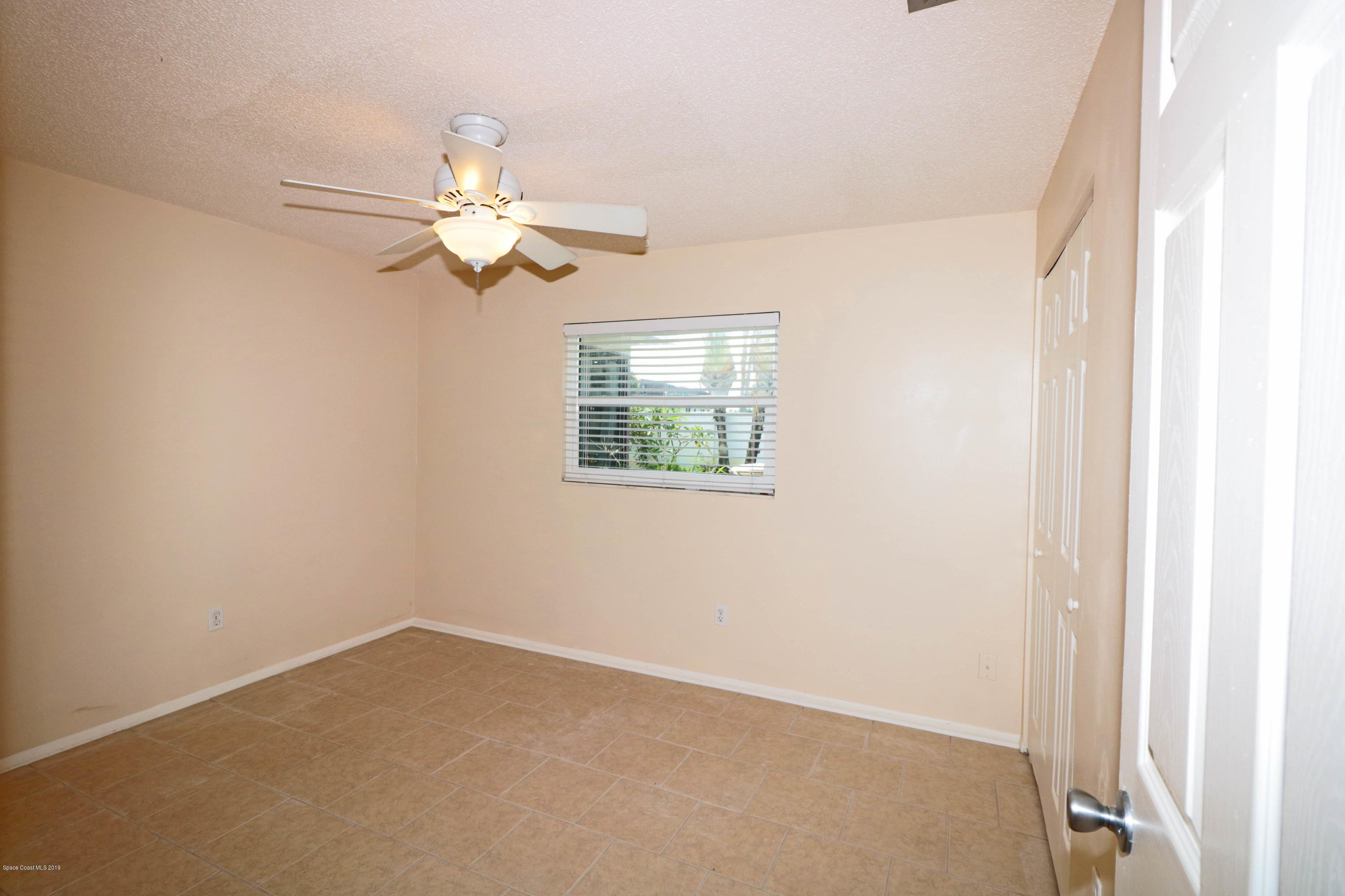 243 Ocean View Lane Melbourne, FL 32903 - Photo 17 of 18 an empty room with a window and a fan
