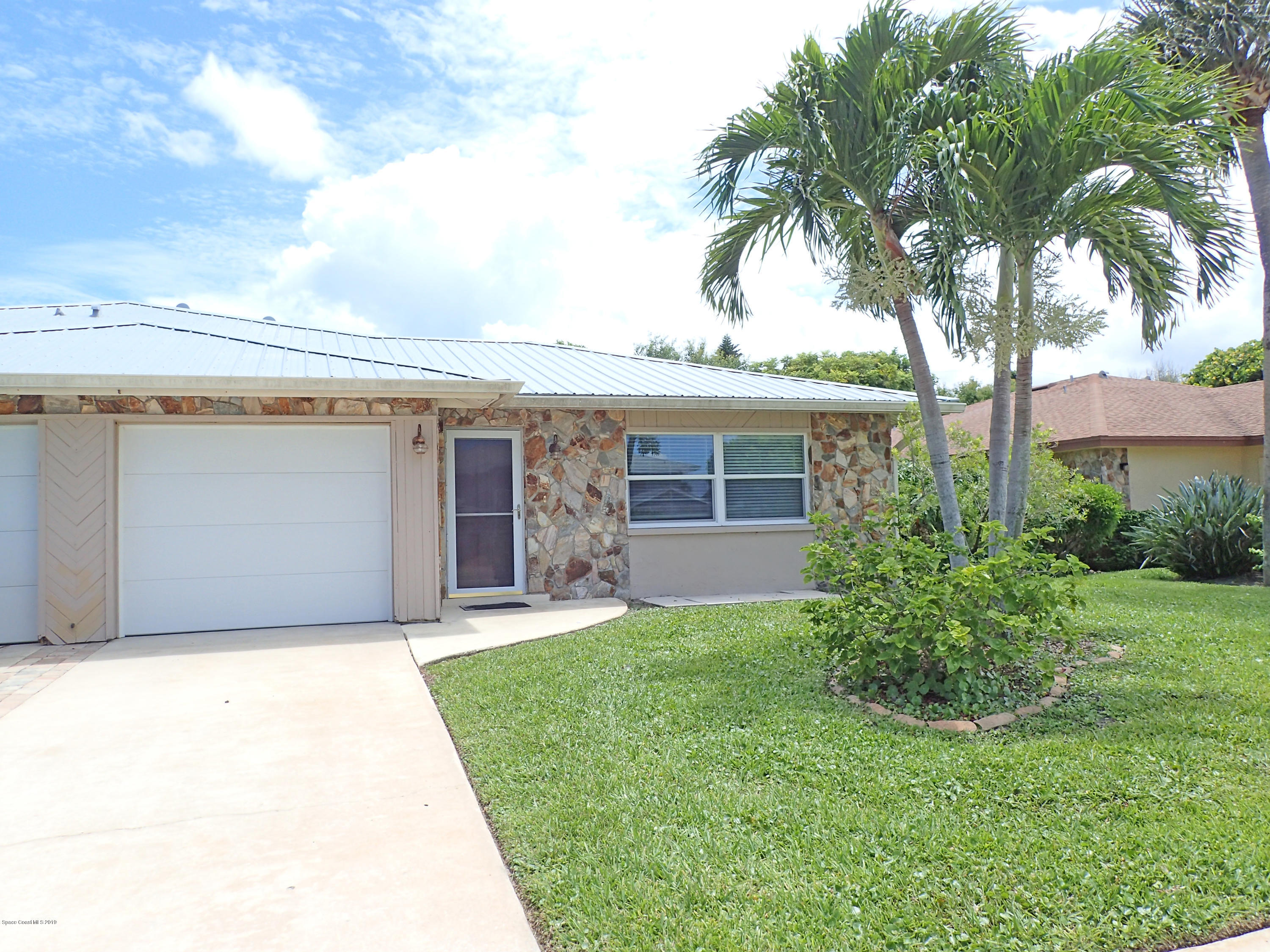 243 Ocean View Lane Melbourne, FL 32903 - Photo 7 of 18 a front view of a house with a garden and trees