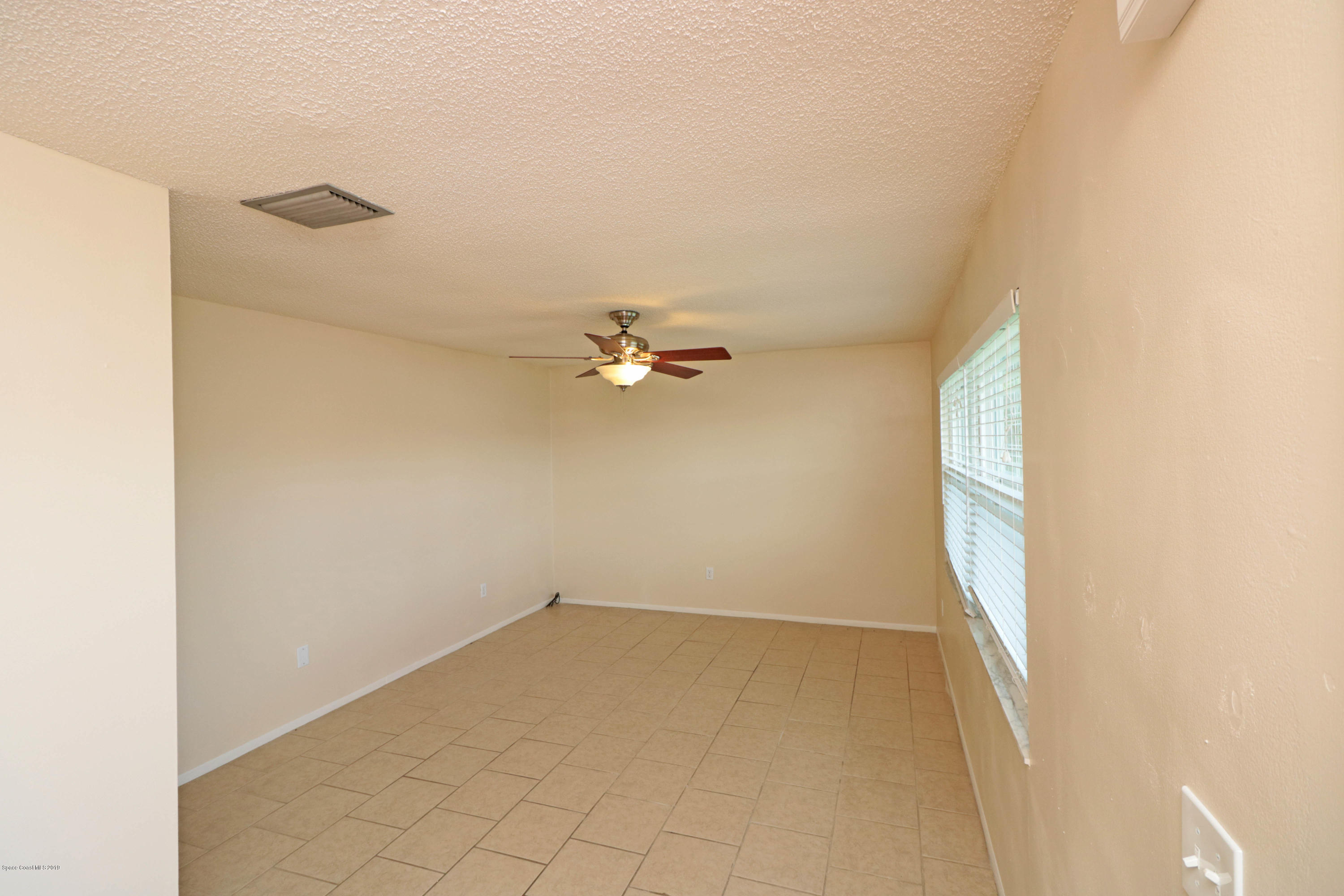 243 Ocean View Lane Melbourne, FL 32903 - Photo 8 of 18 an empty room with a ceiling fan and a window
