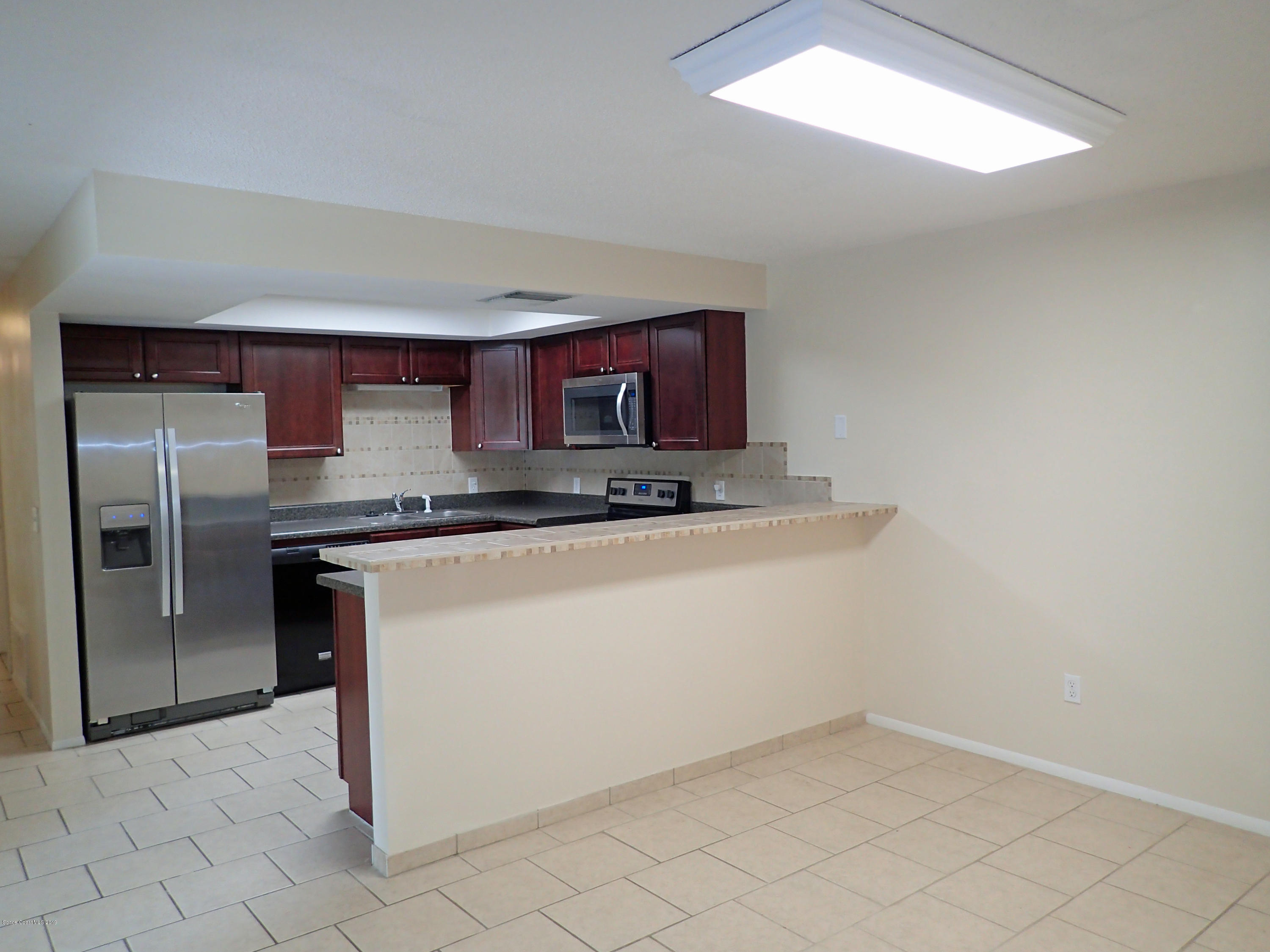 243 Ocean View Lane Melbourne, FL 32903 - Photo 10 of 18 a kitchen with granite countertop a refrigerator a stove and a sink with granite countertops