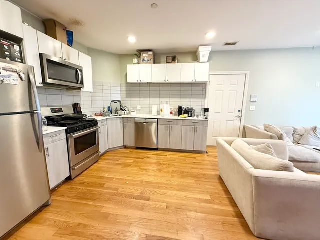 a large kitchen with cabinets wooden floor and stainless steel appliances