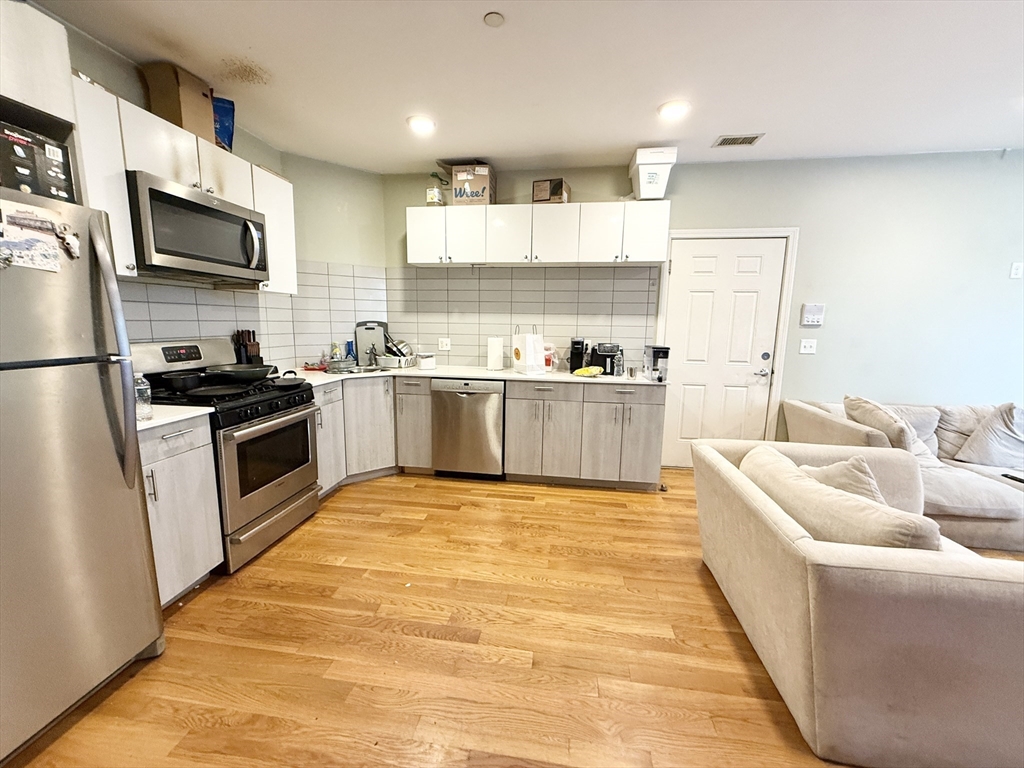 a large kitchen with cabinets wooden floor and stainless steel appliances