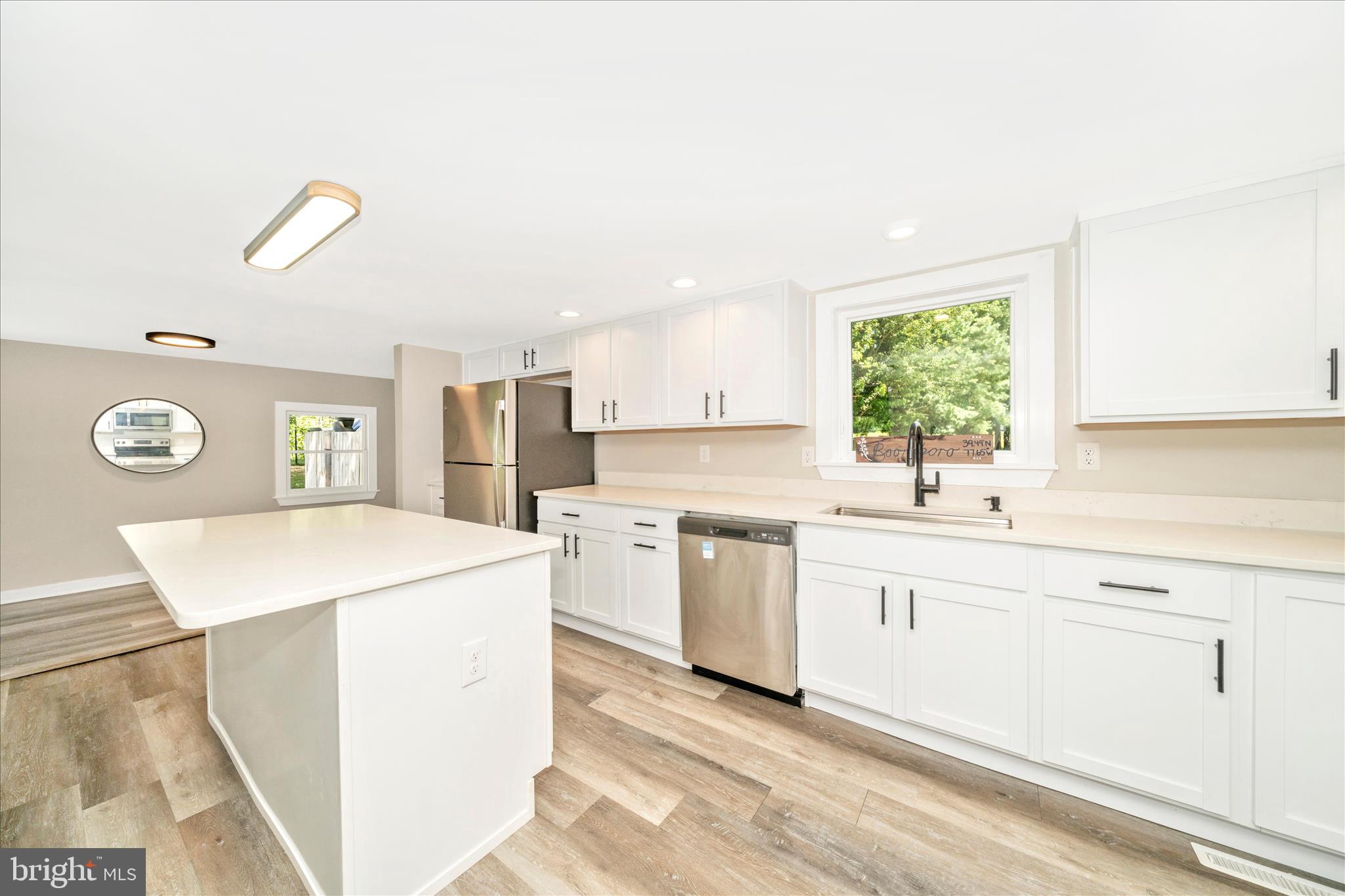 20724 Netz Road Boonsboro, MD 21713 - Photo 13 of 40 a kitchen with a sink a stove a refrigerator and white cabinets with wooden floor