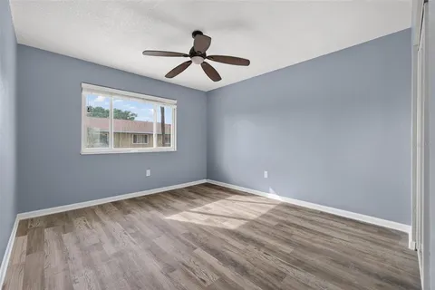 a view of empty room with wooden floor and fan