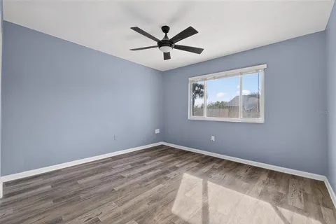 an empty room with wooden floor and ceiling fan