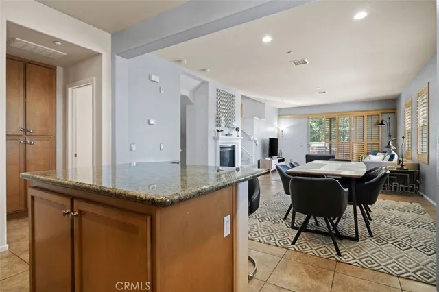 a dining hall with granite countertop a sink dishwasher a dining table and chairs with wooden floor