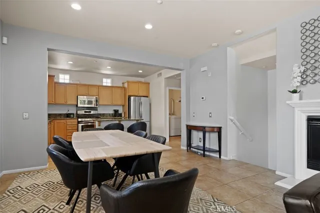 a kitchen with stainless steel appliances kitchen island granite countertop a dining table chairs and a refrigerator