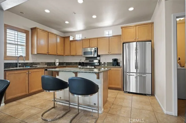 a kitchen with stainless steel appliances granite countertop a refrigerator a stove a sink and a microwave