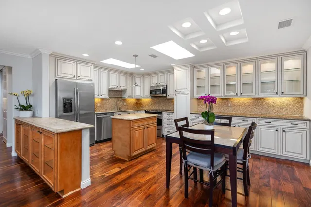 a kitchen with granite countertop a table chairs stove microwave and cabinets