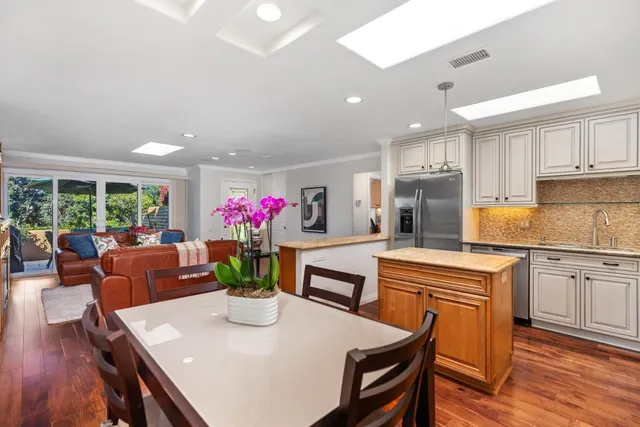 a kitchen with stainless steel appliances granite countertop a dining table chairs and granite counter tops