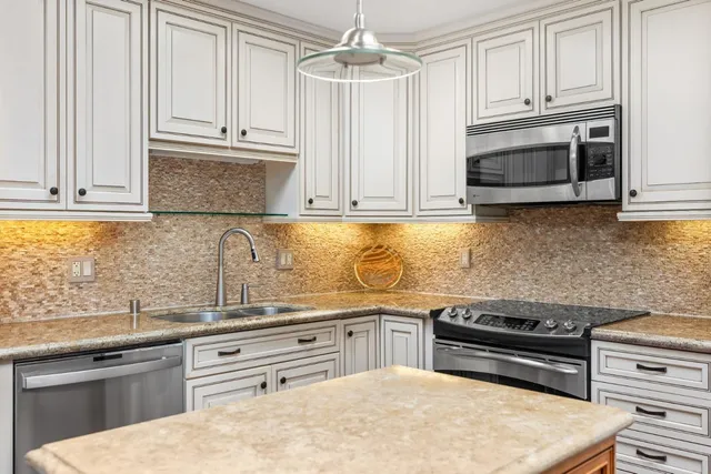 a kitchen with stainless steel appliances granite countertop a stove a sink and a microwave