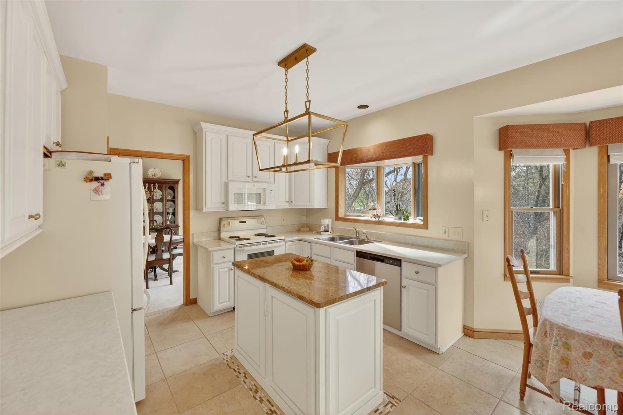 7798 Lee Road Brighton, MI 48116 - Photo 10 of 49 Kitchen featuring white appliances, white cabinets, hanging lights, a kitchen island, and light tile patterned floors