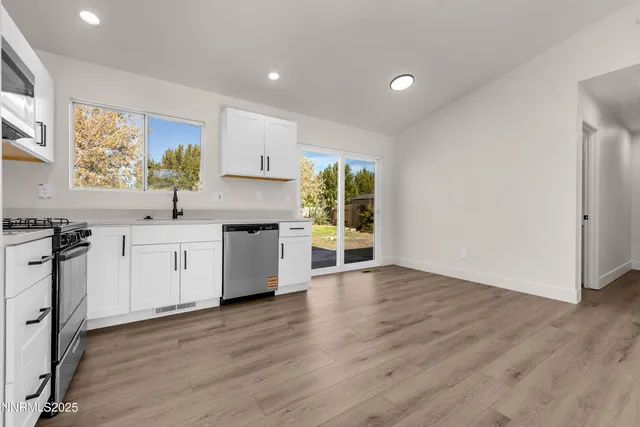 a kitchen with stainless steel appliances granite countertop a sink a stove and a wooden floors