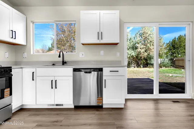 a kitchen with stainless steel appliances granite countertop white cabinets a microwave a stove and a sink