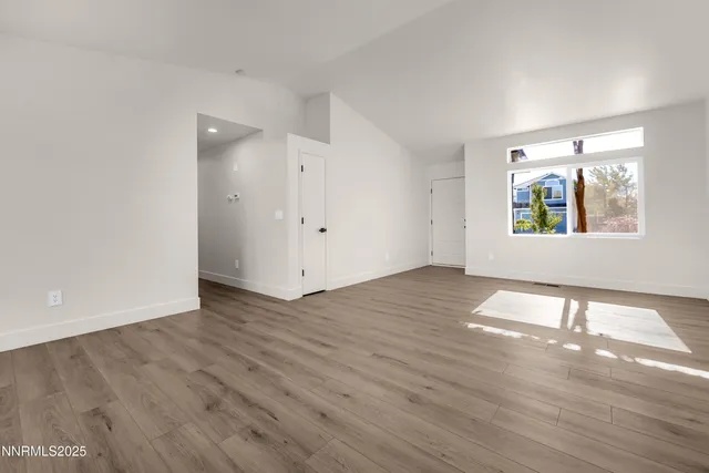 an empty room with wooden floor closet and windows