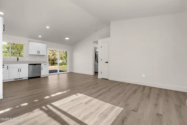 a kitchen with stainless steel appliances a microwave a stove a sink dishwasher a refrigerator and white cabinets with wooden floor