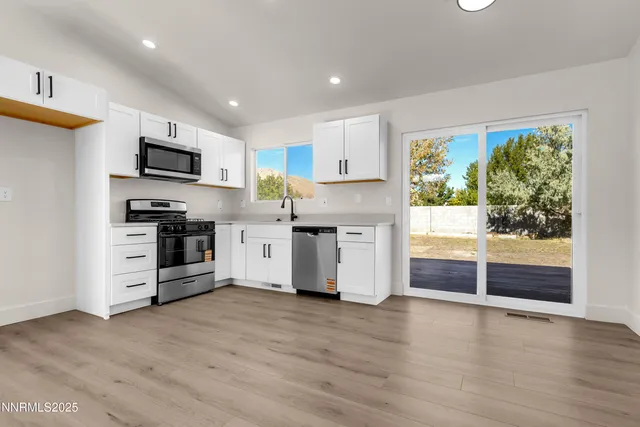 a kitchen with a sink cabinets wooden floor and stainless steel appliances