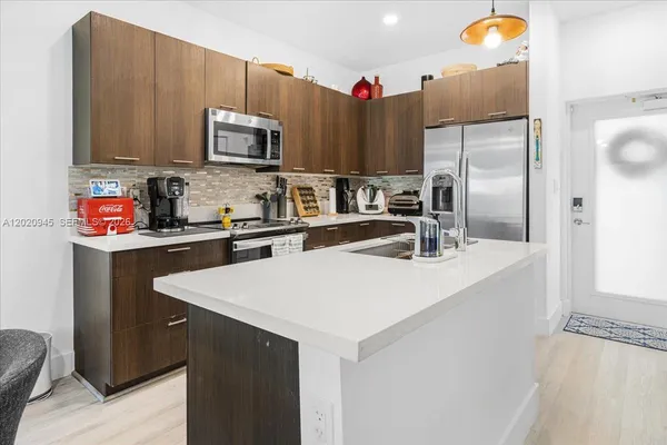 a kitchen with stainless steel appliances a sink a stove a microwave a refrigerator and cabinets