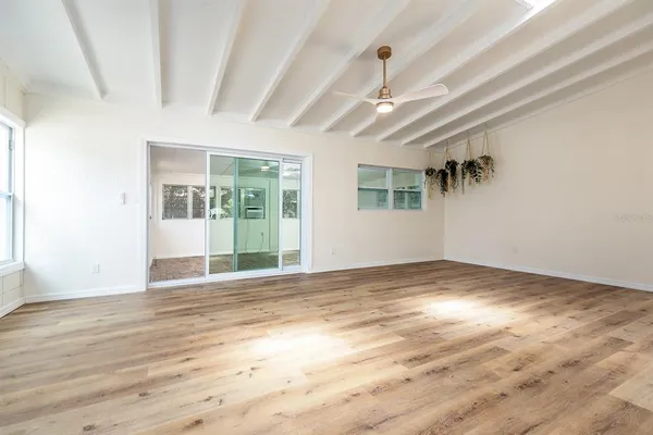 a view of an empty room with wooden floor and a window