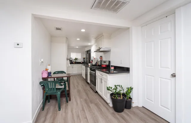 a kitchen with stainless steel appliances granite countertop a stove a sink dishwasher and cabinets with wooden floor