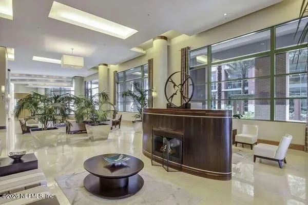 a living room with furniture a flat screen tv and a refrigerator