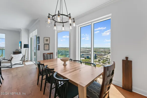 a view of a dining room and livingroom with furniture wooden floor a chandelier