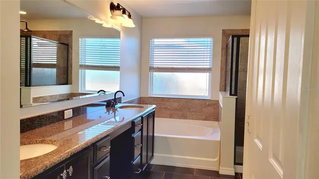a bathroom with a granite countertop sink a bathtub and next to a window