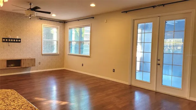a view of an empty room with wooden floor and a window