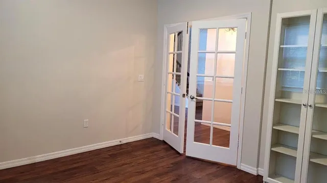 a view of an empty room with wooden floor and windows