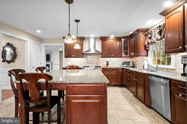 a kitchen with stainless steel appliances granite countertop a stove top oven a sink a dining table and chairs with wooden floor