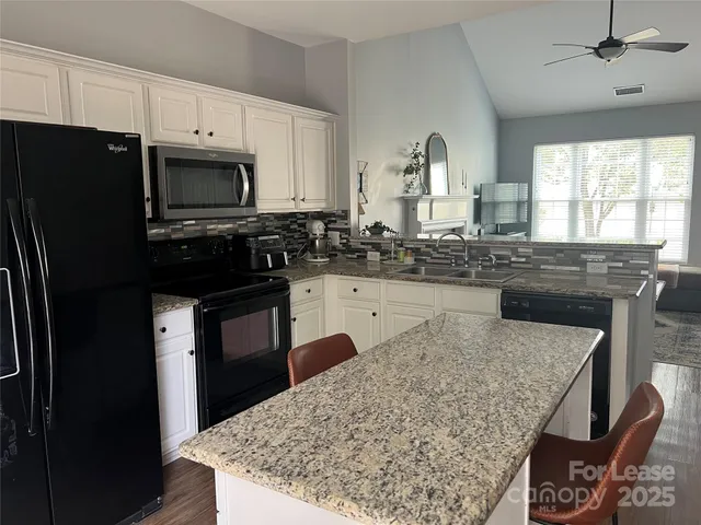 a kitchen with stainless steel appliances granite countertop a stove refrigerator sink and microwave