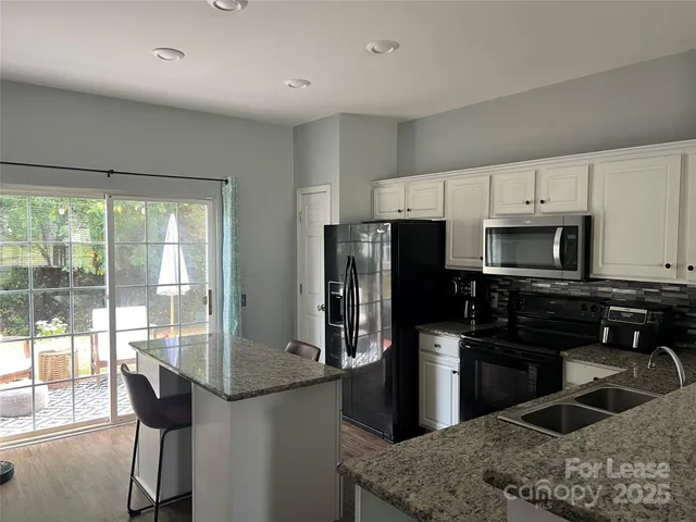 a kitchen with granite countertop a sink stainless steel appliances and cabinets