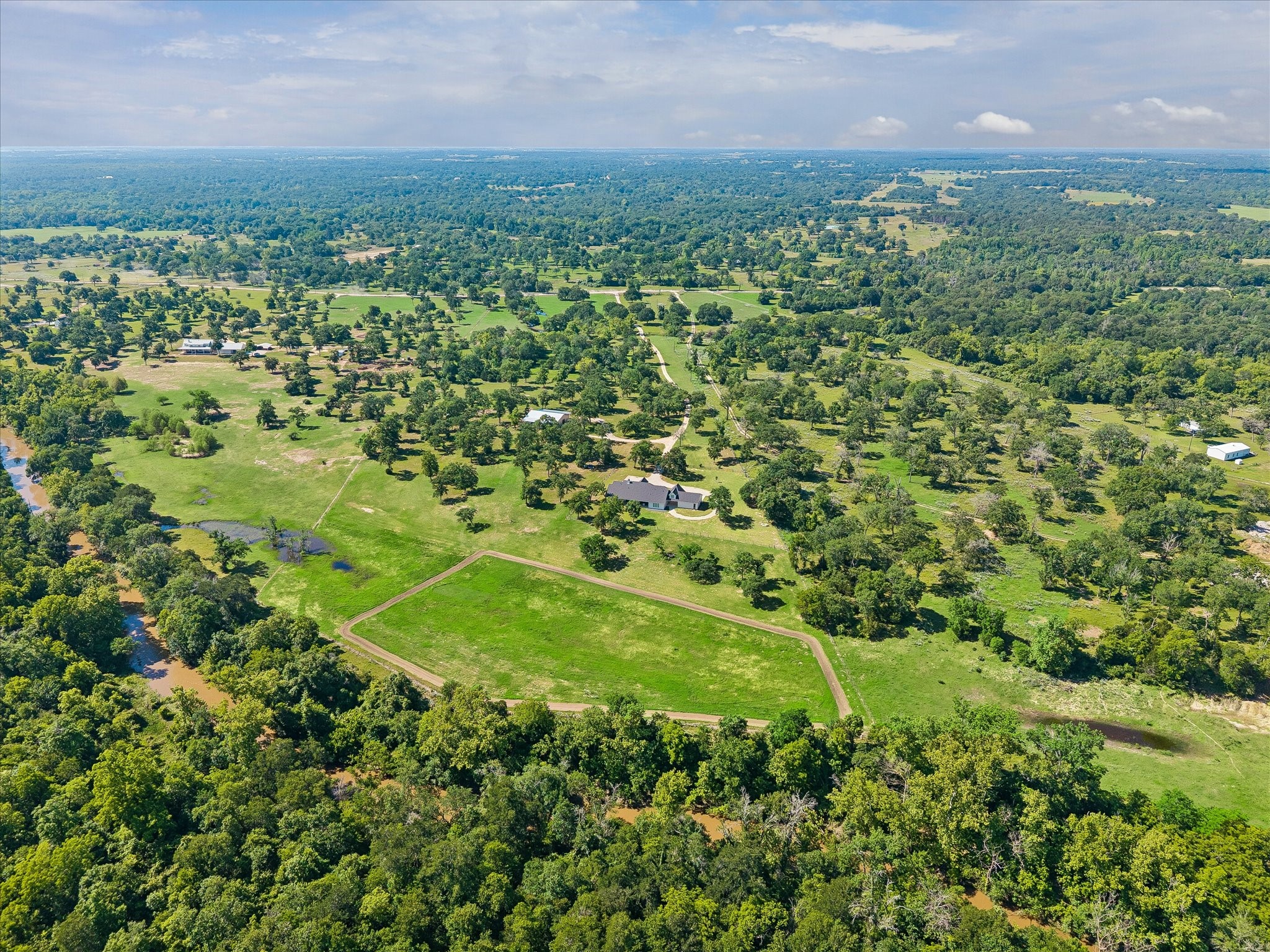 4052 Kuykendall Road Bellville, TX 77418 - Photo 35 of 40 This aerial photo showcases a sprawling property with lush greenery, open fields, and scattered trees, offering a serene and expansive landscape. The house sits centrally, surrounded by nature, offering ideal privacy.