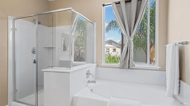 a bathroom with a shower a window and a tub