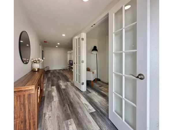 a view of a hallway with wooden floor and a bathroom