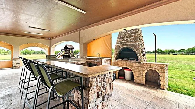 a view of a patio with table and chairs a barbeque with wooden floor and fence