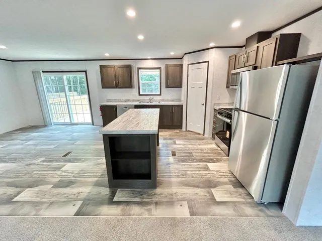 a kitchen with stainless steel appliances granite countertop a refrigerator a stove and a sink