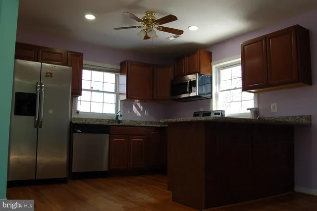 a kitchen with stainless steel appliances granite countertop a refrigerator a sink a stove a microwave and wooden cabinets