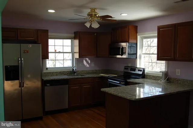 a kitchen with stainless steel appliances granite countertop a sink a stove a refrigerator cabinets and a window