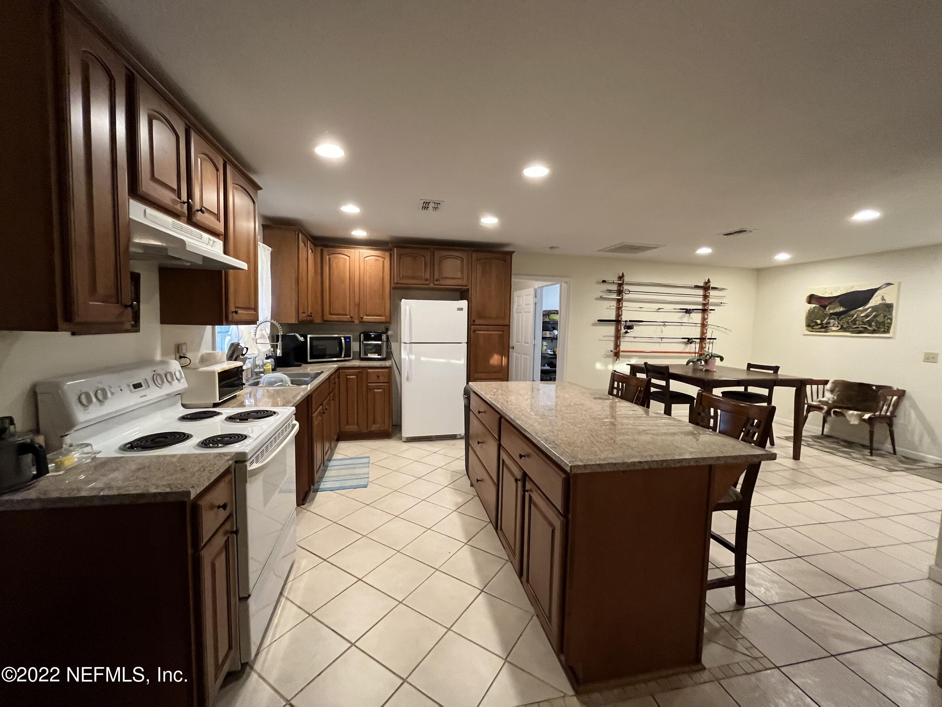 75049 Edwards Road Yulee, FL 32097 - Photo 6 of 23 a kitchen with stainless steel appliances granite countertop a table chairs a refrigerator and a sink