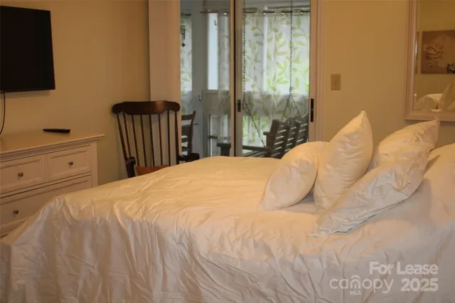 a bedroom with a bed and a flat tv screen next to a window