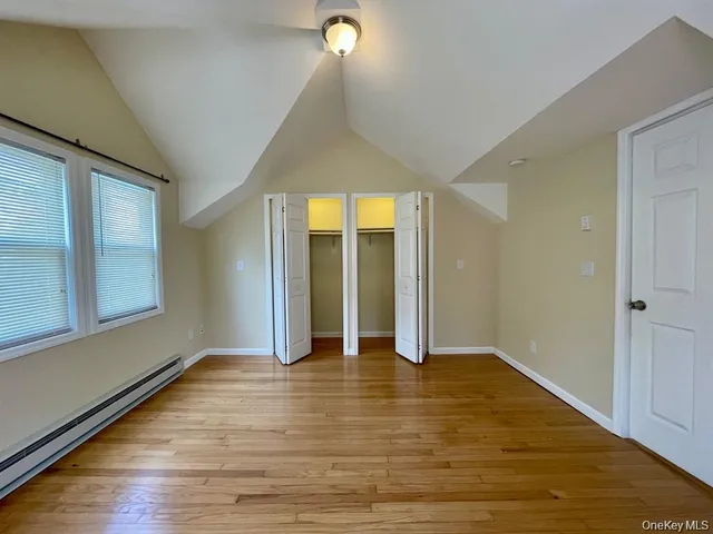 a view of an empty room with window and wooden floor