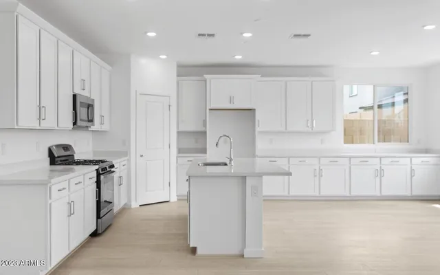 a kitchen with stainless steel appliances granite countertop a stove top oven a sink a refrigerator and white cabinets