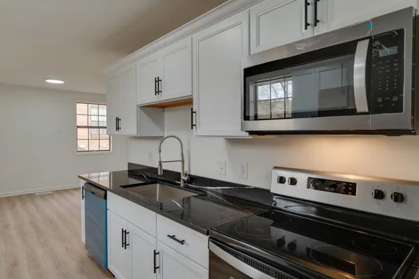 a kitchen with granite countertop a stove microwave and sink