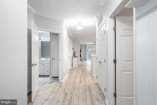 a view of a hallway with wooden floor a bathroom and a sink