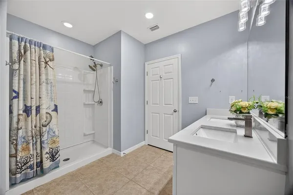 a hallway with a sink a chandelier and a dining table
