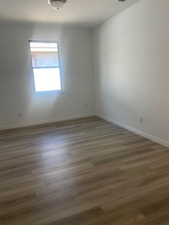 1825 Plymouth Drive Princeton, TX 75407 - Photo 16 of 23 a view of an empty room with wooden floor and a window